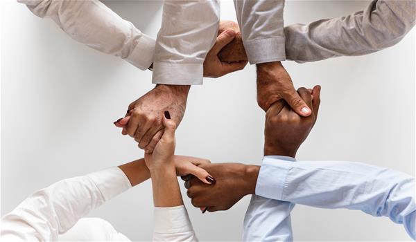 black-collaboration-cooperation-943630 Four diverse people's hands connected in a circle.
