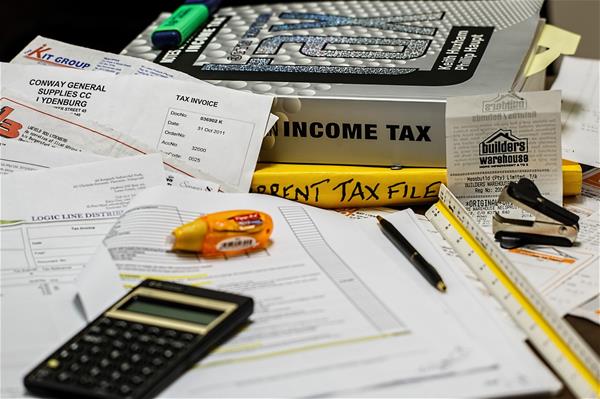 income-tax-491626_1280 A pile of papers and receipts with tax books, a calculator and some office supplies.