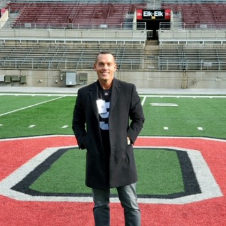 Man on football field smiling for camera.