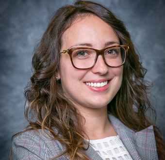 Woman wearing suit and glasses smiling for the camera.